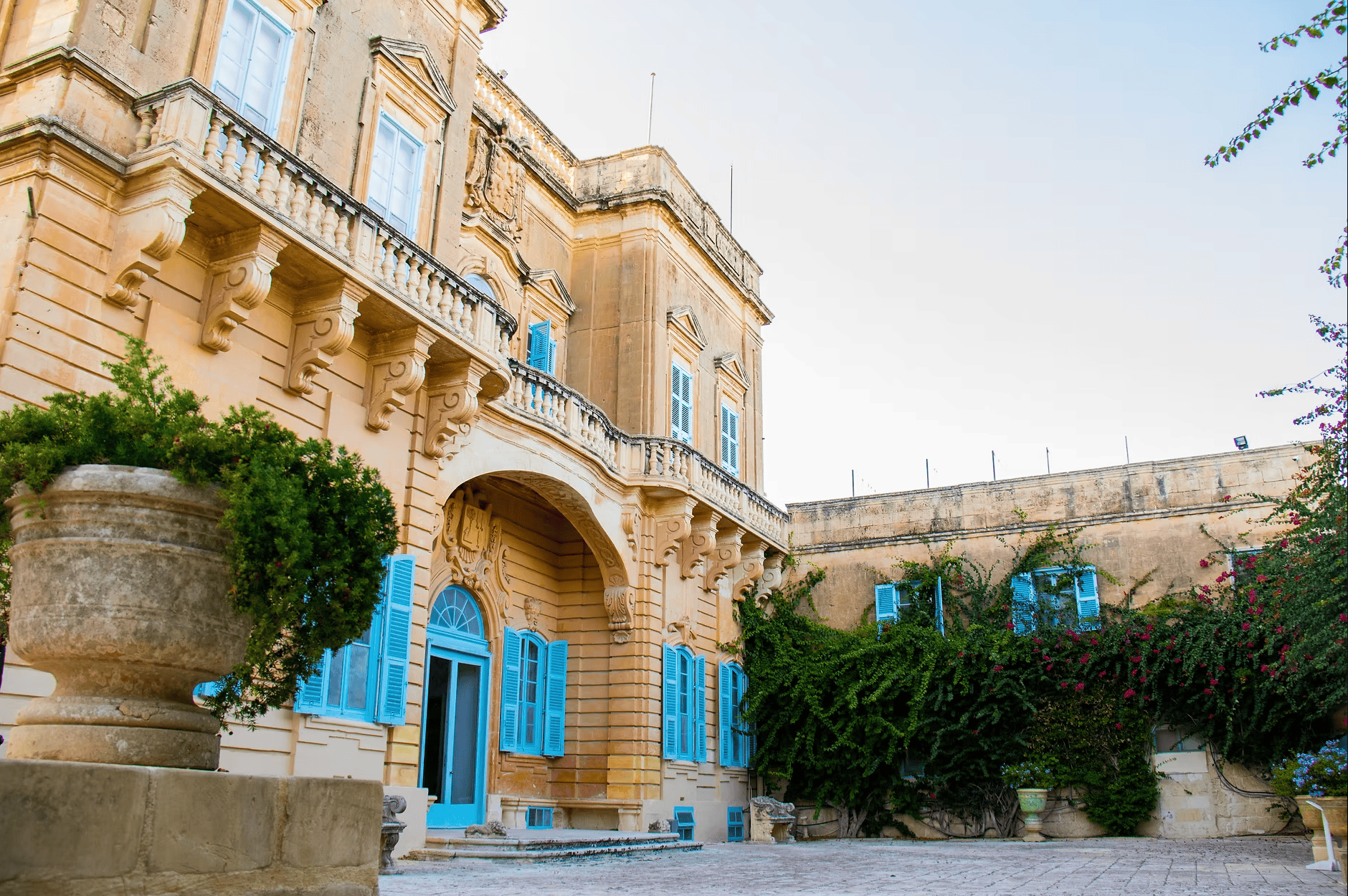 Grand baroque manor house with blue shutters and ornate stone arches